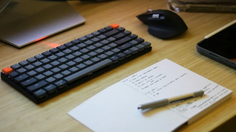 What to Ask Before You Hire a Website Designer for Therapists? The workspace of a individual, featuring a well-organized table with a keyboard, notebook, pencil, mouse, and handwritten notes.