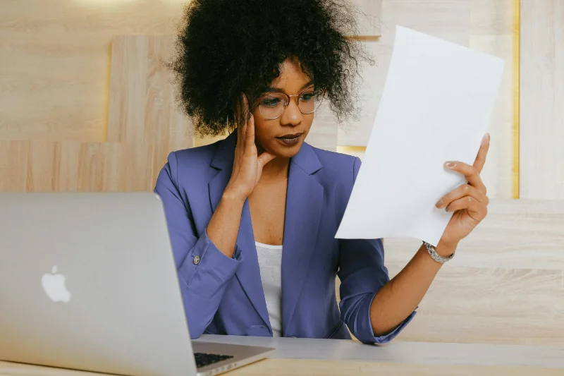 Do You Need a Blog on Your Therapy Website? Woman holding paper while using laptop