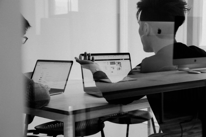 What to Ask Before You Hire a Website Designer for Therapists? A person using Macbook while talking to another person